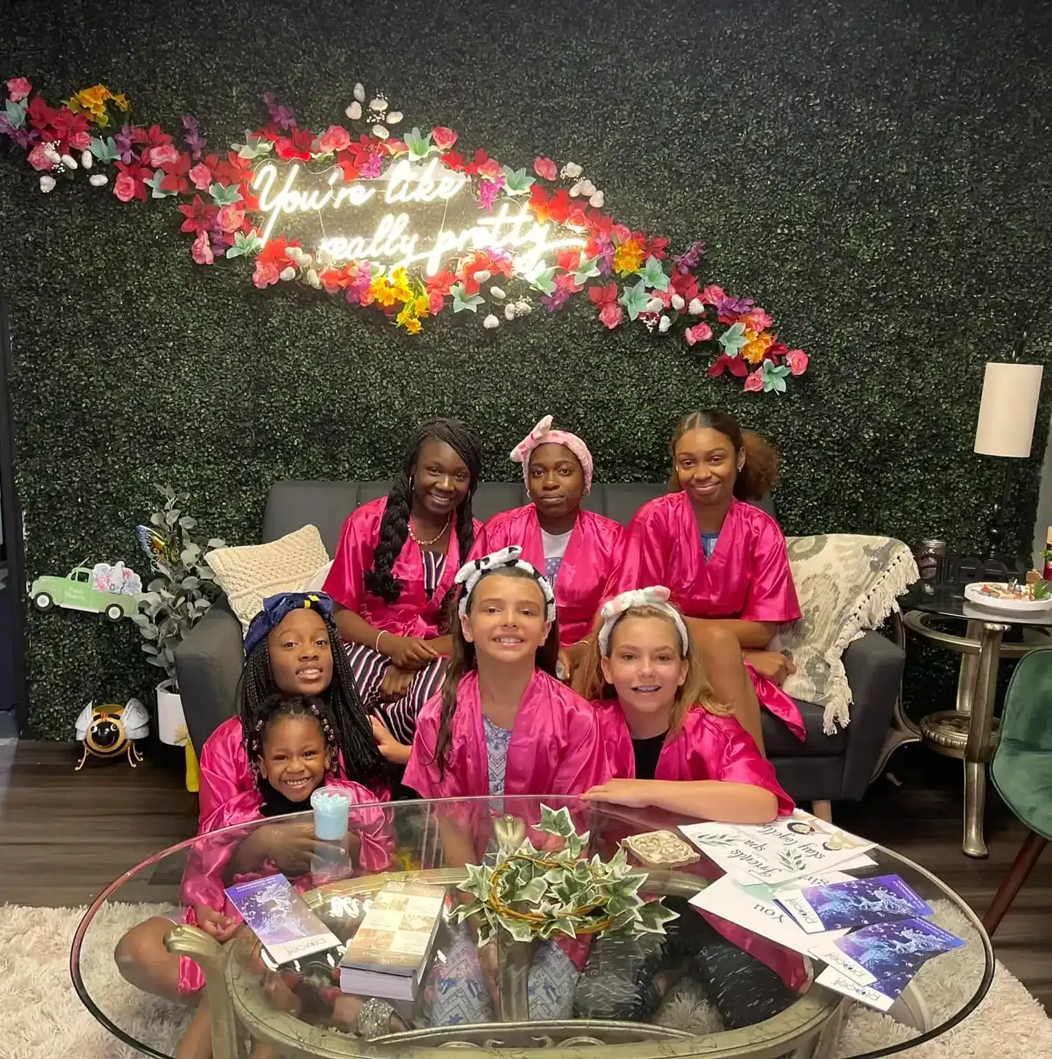 A group of girls are posing for a picture in front of a sign that says you 're like really pretty