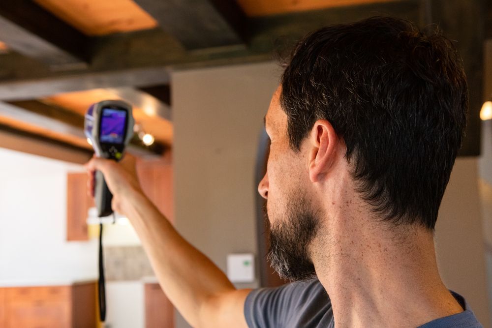 A man is using a thermometer to measure the temperature of a room.