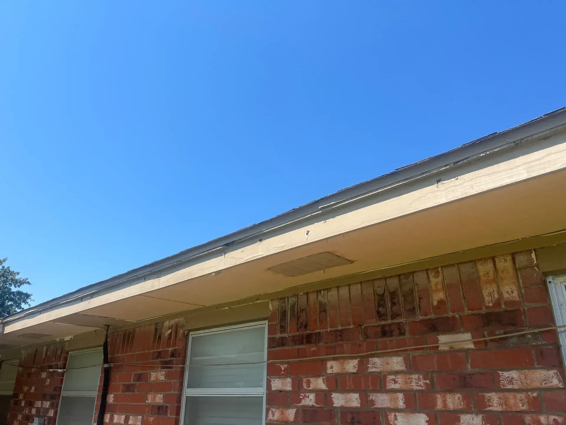 Brick building exterior with beige trim, gutters, and a blue sky.