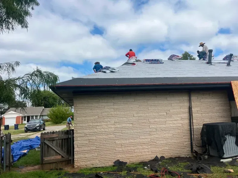 Roofers working on a house under a cloudy sky.