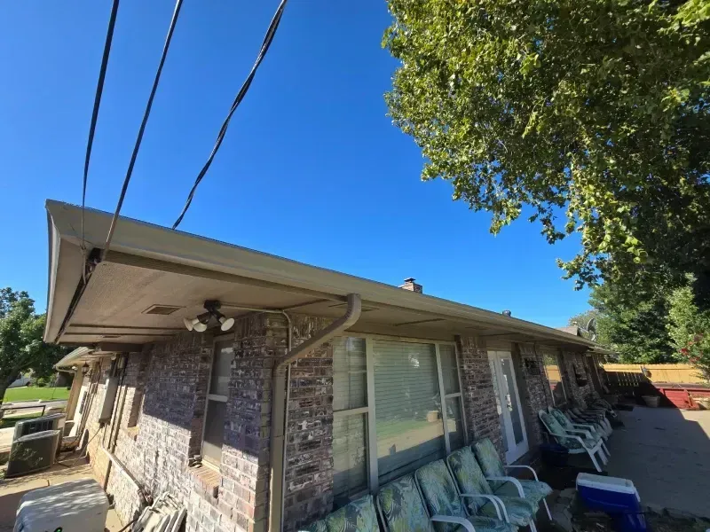 Low-angle view of a one-story brick building with a porch, blue sky, and utility lines.