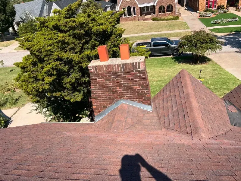 View from a roof of a brick chimney with two orange caps.