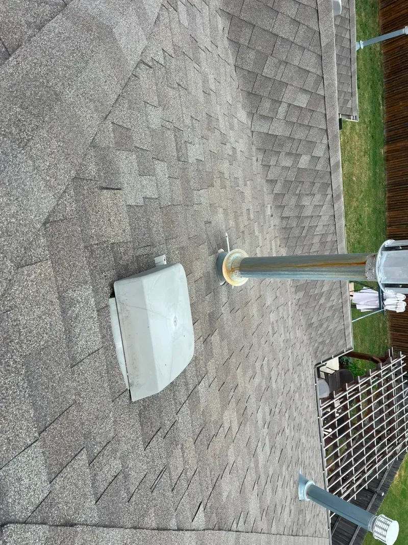 Gray roof shingles with a gray outdoor electrical box and a metal pole attached.