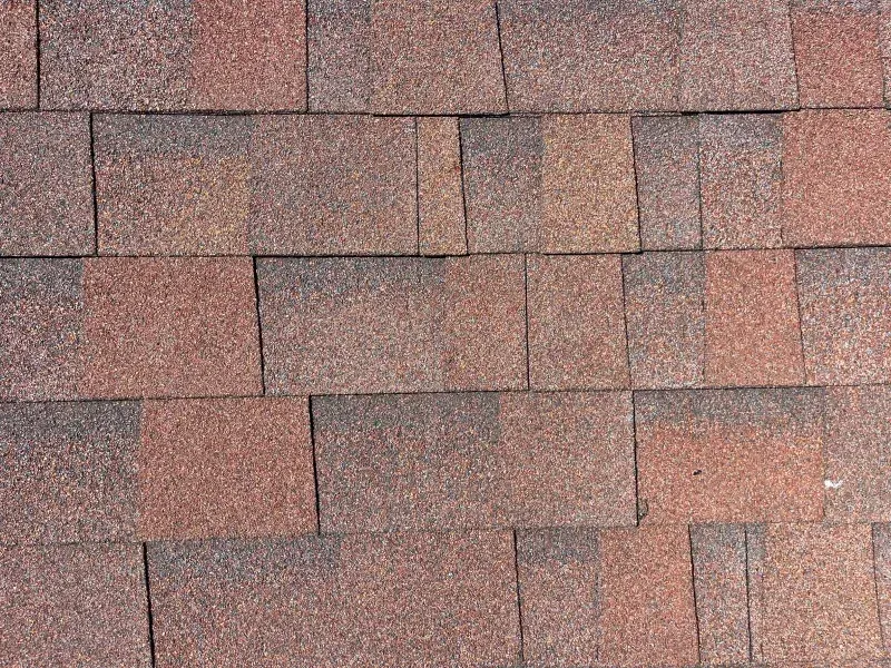 Brown and reddish-brown asphalt roof shingles arranged in overlapping rows.