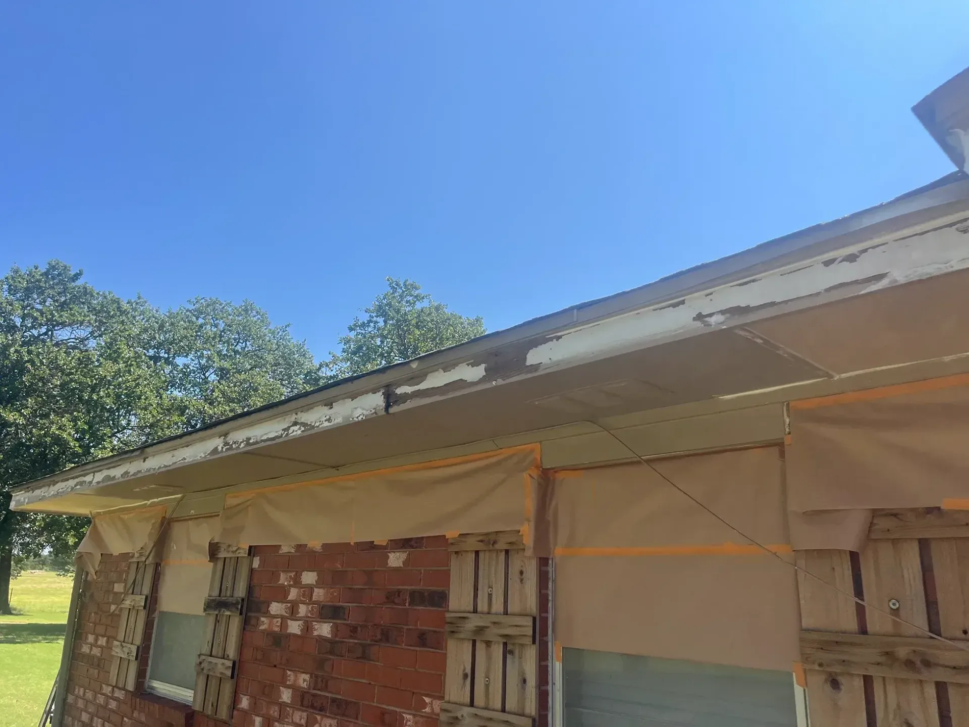 Exterior shot of a brick building with peeling white trim under a clear blue sky.