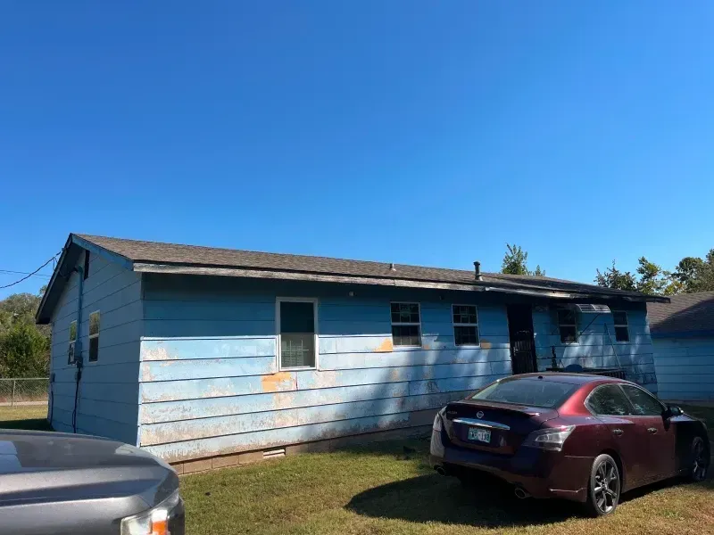 Blue house with car in front, under a clear blue sky.