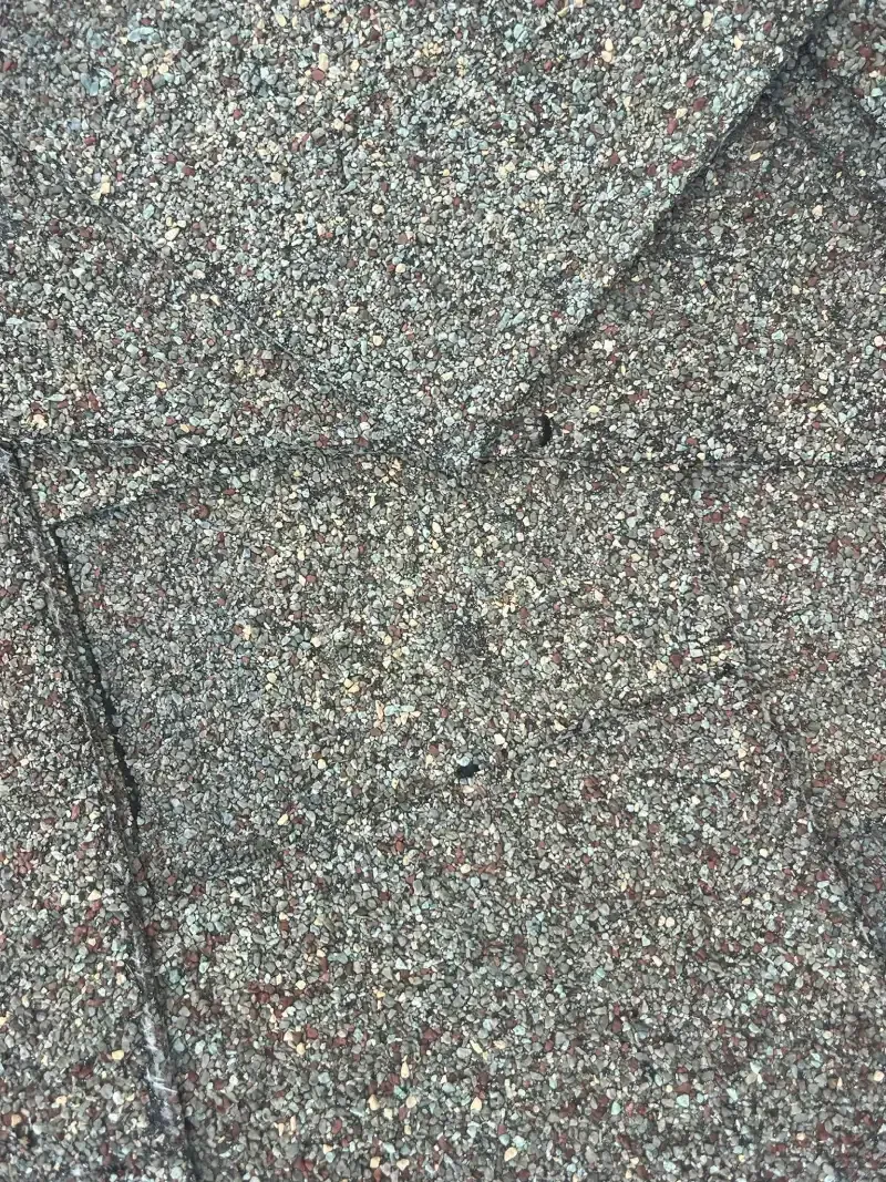 Close-up of a grainy, dark grey surface with angled, textured lines, suggesting a building material.