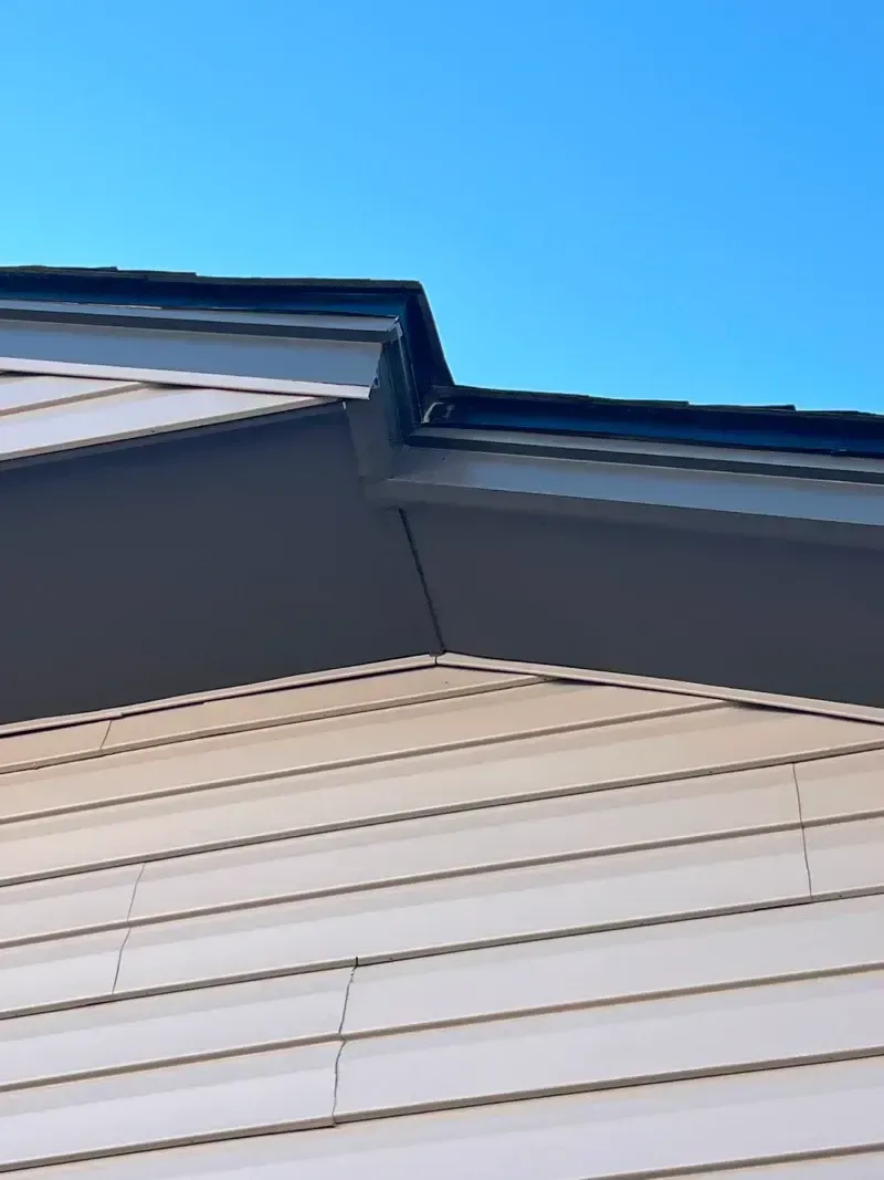 Beige siding and dark roof under a blue sky.