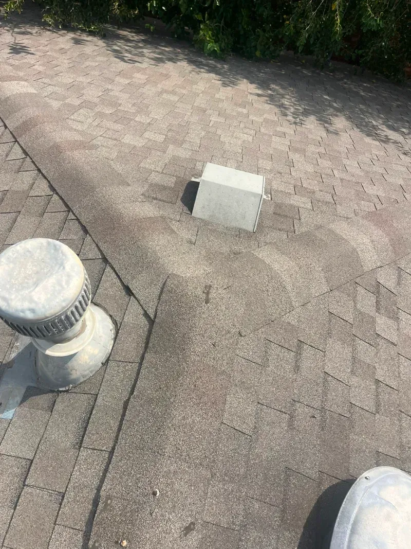 Gray asphalt shingle roof with two vents and a rectangular box-shaped structure.