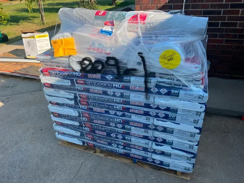 Pallet of building materials wrapped in plastic, labeled 