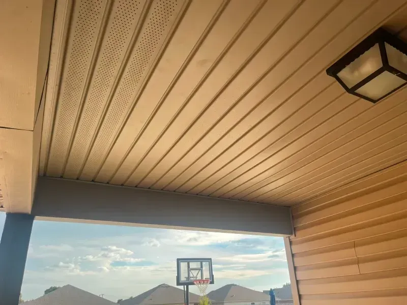Tan siding and ceiling over an outdoor space; basketball hoop visible outside.