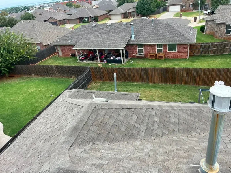 Overhead view of several houses with brown roofs, brick siding, and wooden fences.