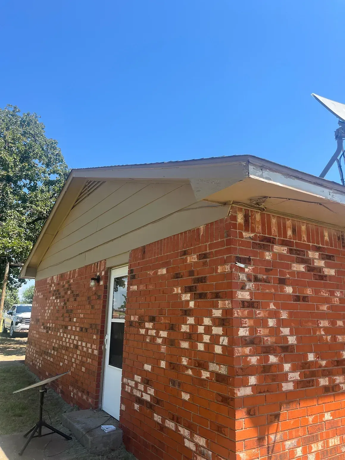 Brick building with a tan roof and trim, under a clear, blue sky.