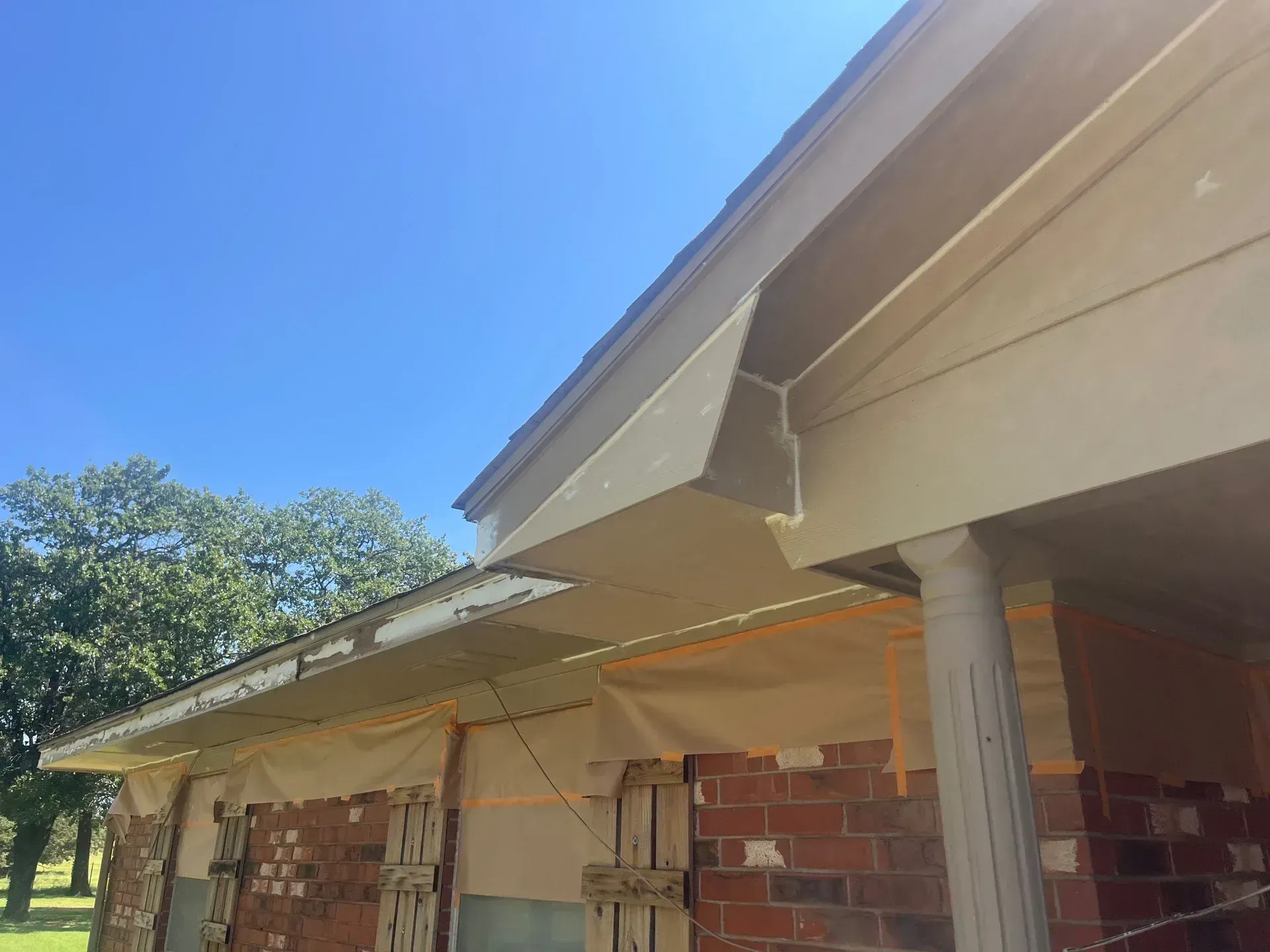House under construction with exposed brick, tan supports, and a blue sky.