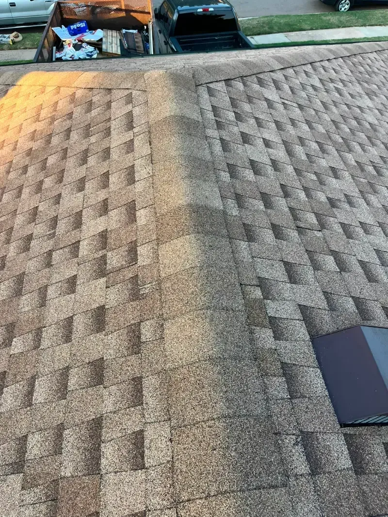 Overhead view of a brown shingle roof with a dark central line and a rectangular vent.
