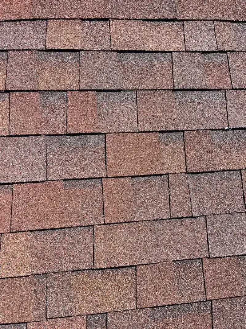Close-up of brown asphalt roof shingles with varying color tones.