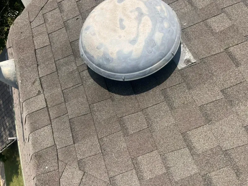 Gray roof vent on a brown shingle roof.