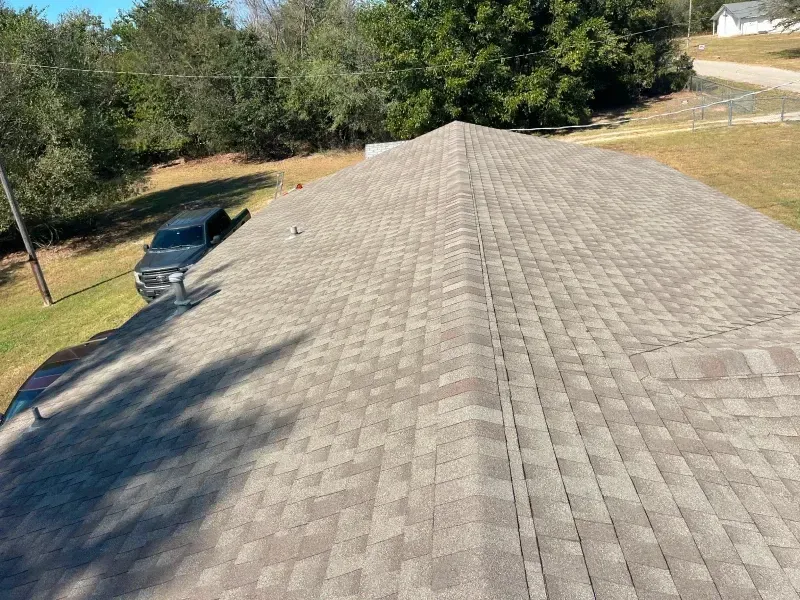 View of a house roof covered in gray shingles with a black truck parked on the side.