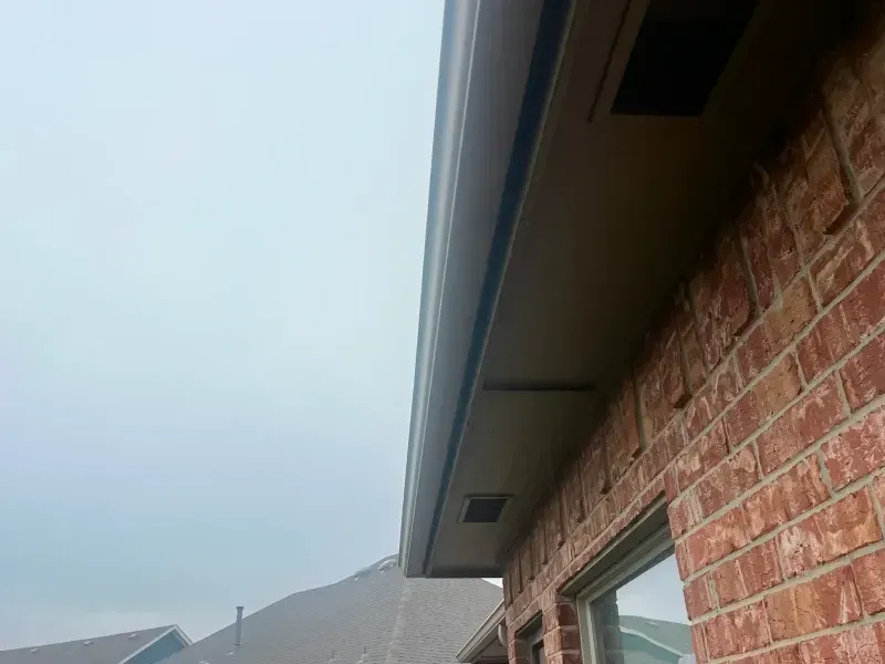 Brown brick exterior with brown overhang and cloudy sky.