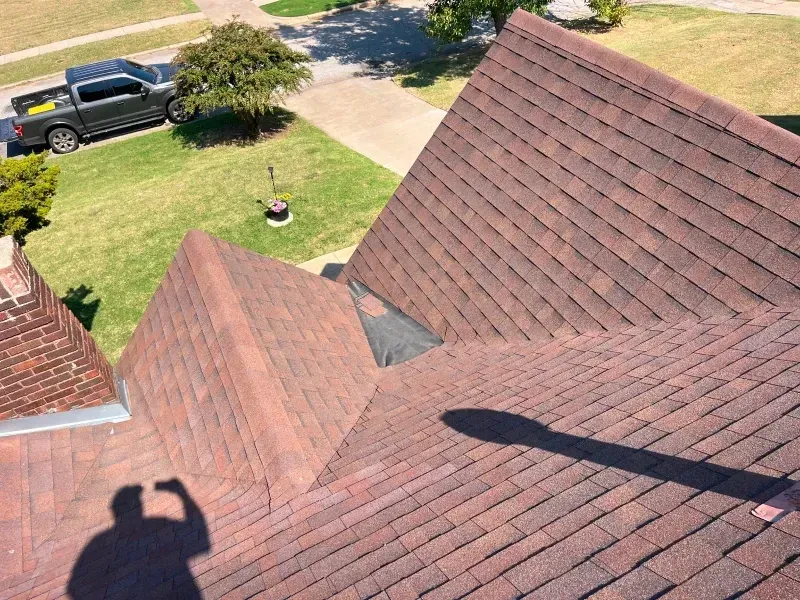 Brown shingled roof with a dark shadow and a view of grass, a truck, and a tree.