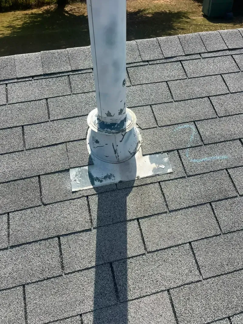 White vent pipe on a gray shingle roof.