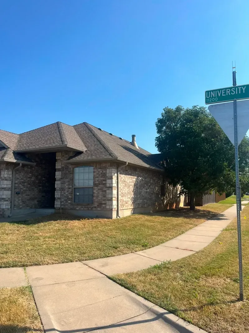 A brick house on a corner lot. A street sign reads 