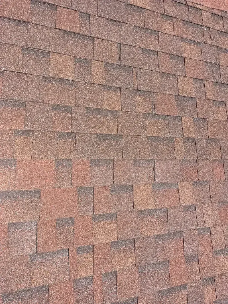 Close-up of a brick-colored asphalt shingle roof.
