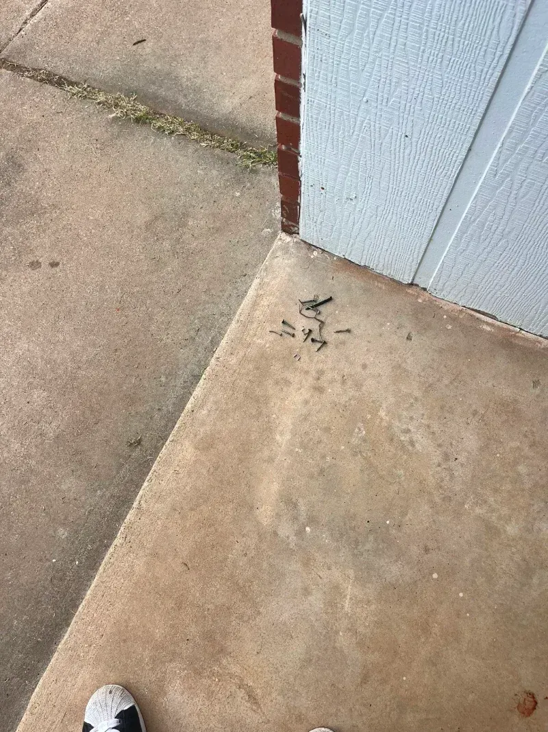 Concrete corner with dark spots near a brick wall and white paneling.  Black and white shoe in the bottom.