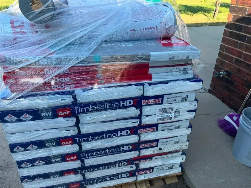 Pallet of GAF Timberline HD roofing shingles wrapped in plastic, ready for installation.
