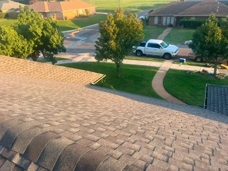 View from a roof, looking at houses, a truck, and trees on a sunny day.
