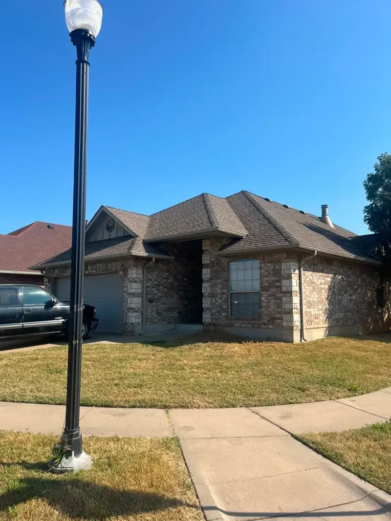 Suburban house with brick facade and tile roof on a sunny day.