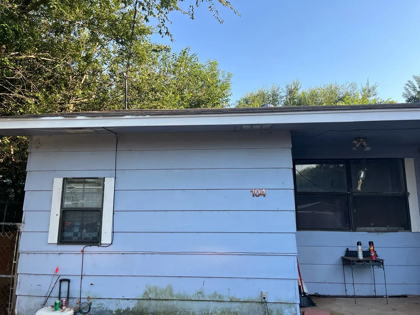 Blue house exterior with window, trees in background.