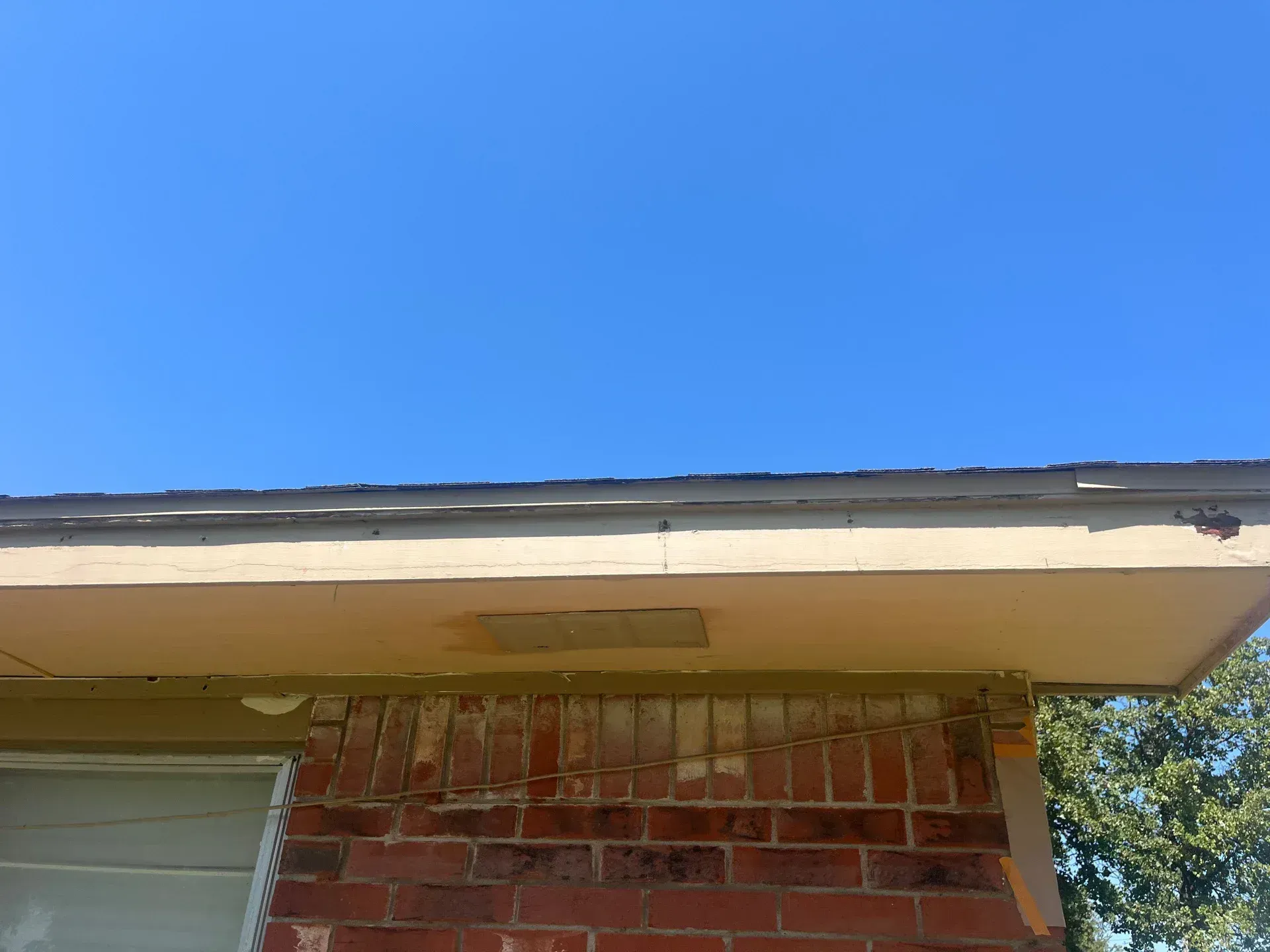 Brick building exterior with a light-colored overhang against a blue sky.