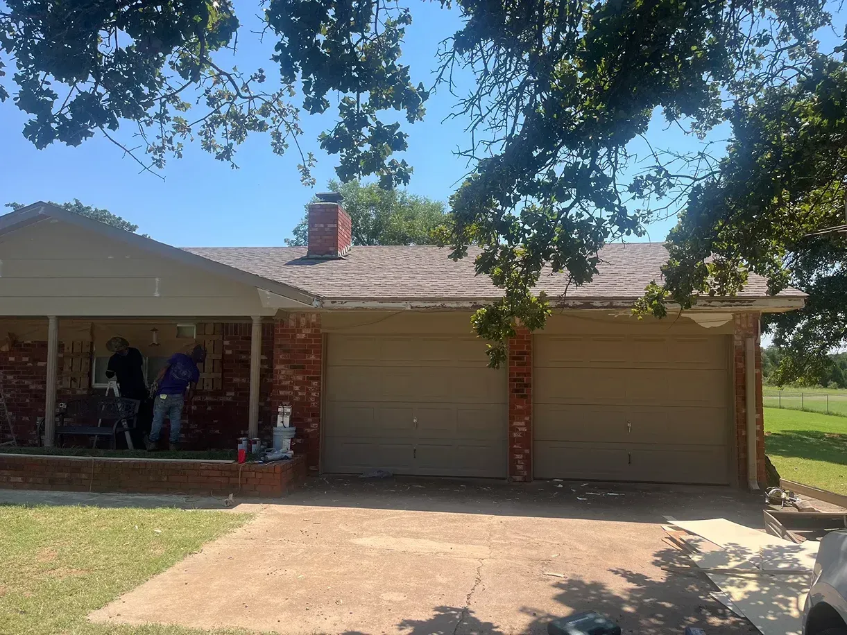 Brick house with a two-car garage, red brick chimney, and people on the porch.
