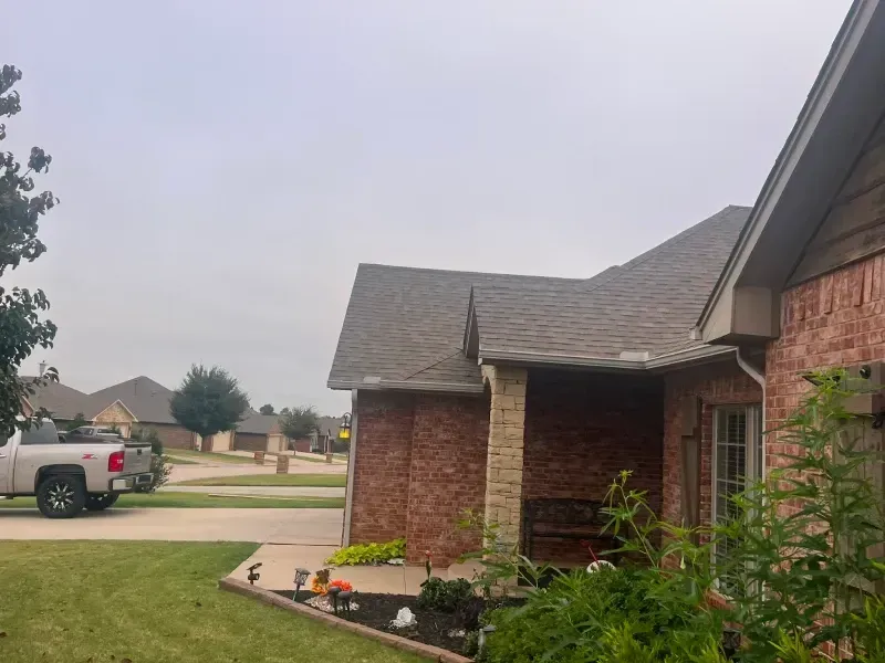 Red brick house with a brown roof and a white truck parked on the street.