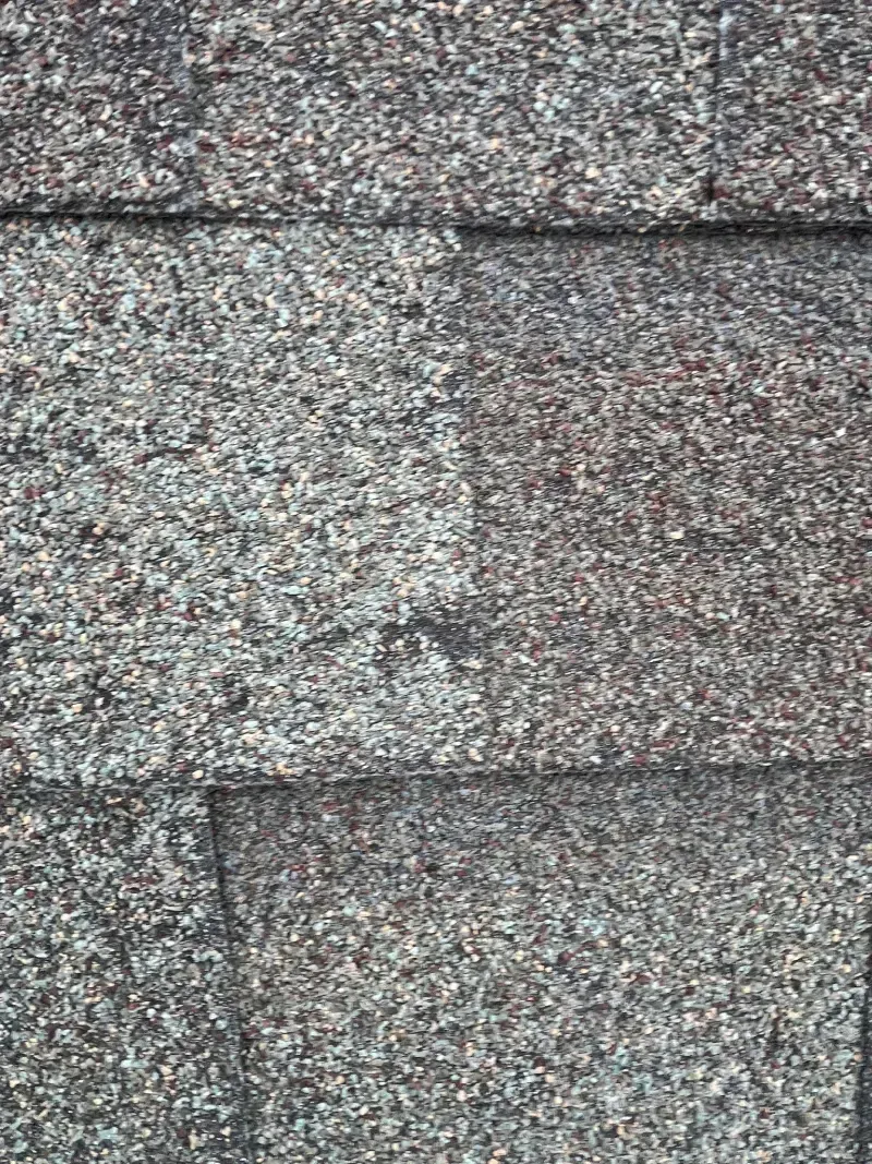 Gray, textured stone wall with horizontal lines, showing rough, granular surface.