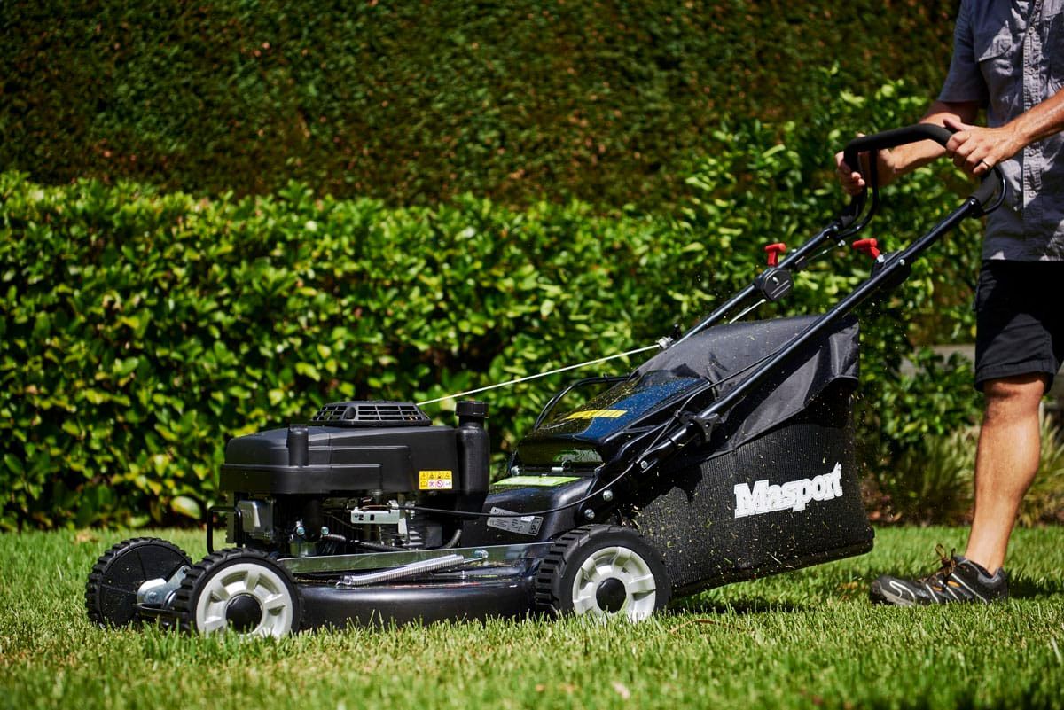 Person Mowing a Green Lawn With a Black Lawnmower — Professional Small Engines in Bowen, QLD