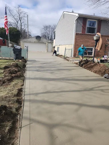 A man is working on a concrete driveway in front of a house.