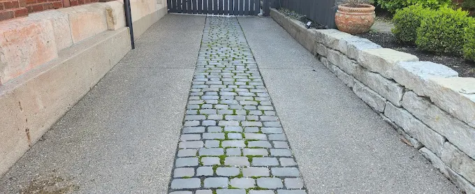A brick walkway leading to a building with a stone wall.