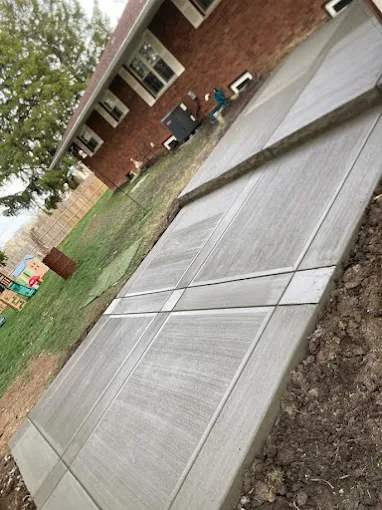 A concrete walkway is being built in front of a brick house.