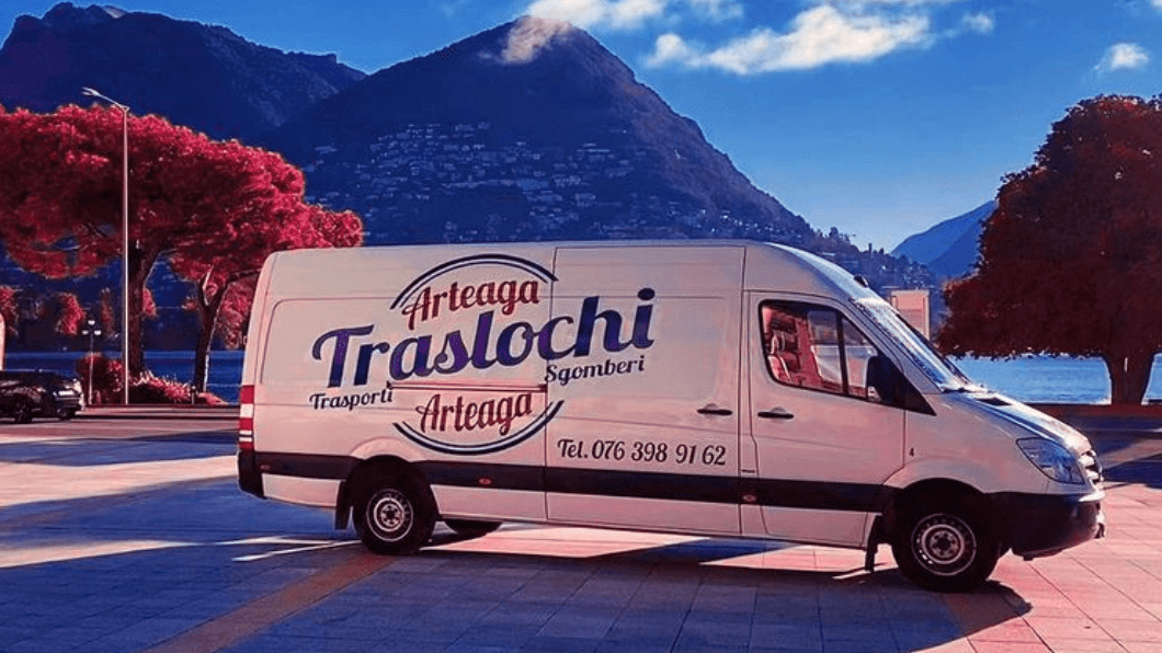 a white van Arteaga Traslochi is parked on the side of the road with mountains in the background .