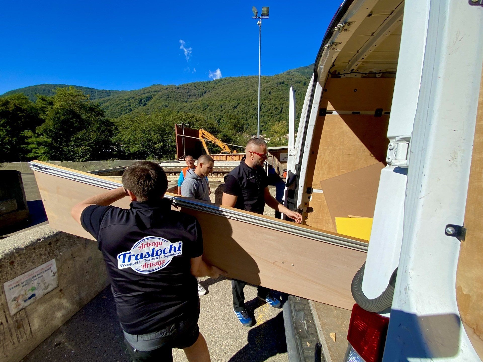 un gruppo di uomini sta caricando un pezzo di cartone in un furgone  per uno sgombero