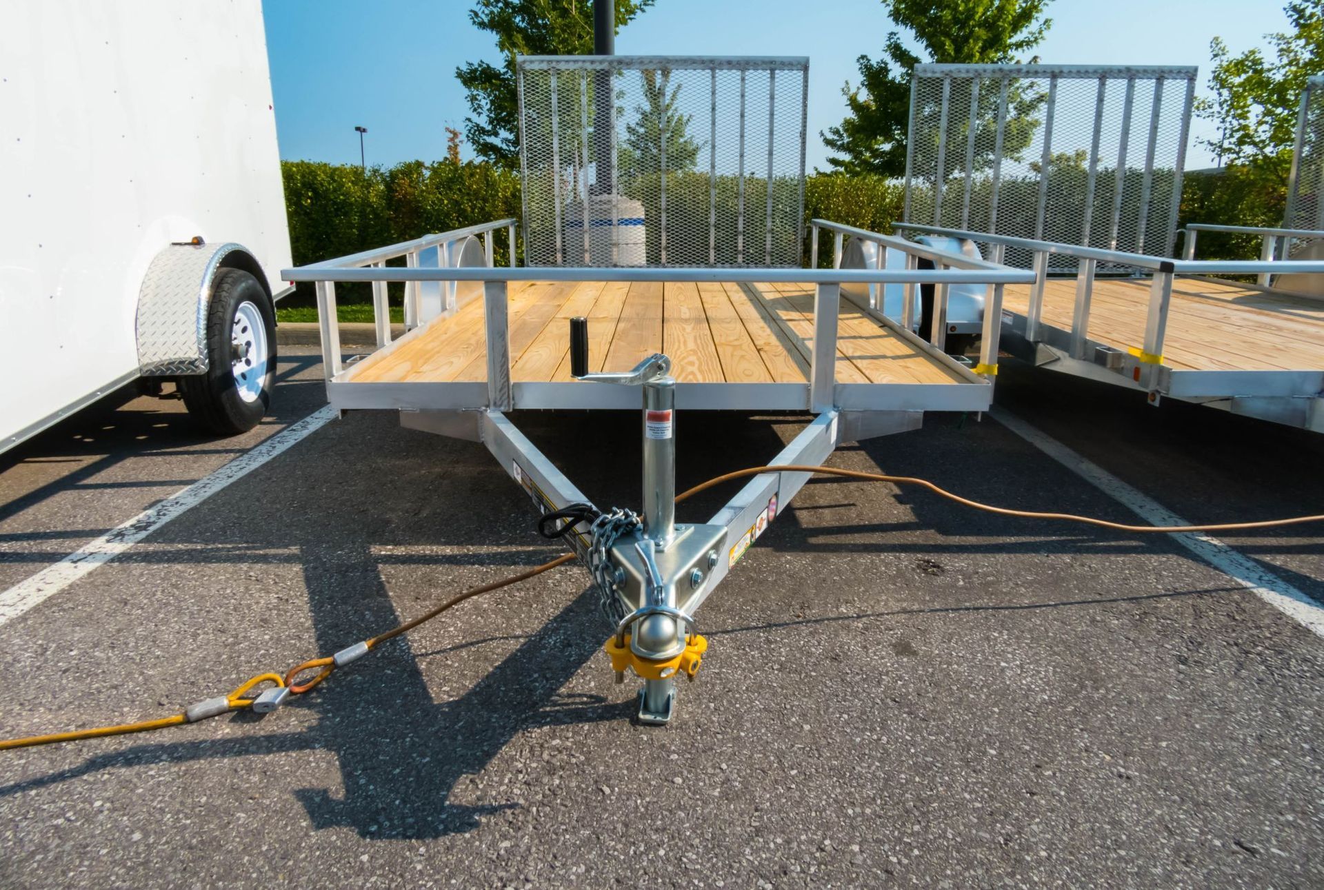 Woman in straw hat smiles, holding wine glass near a lake.