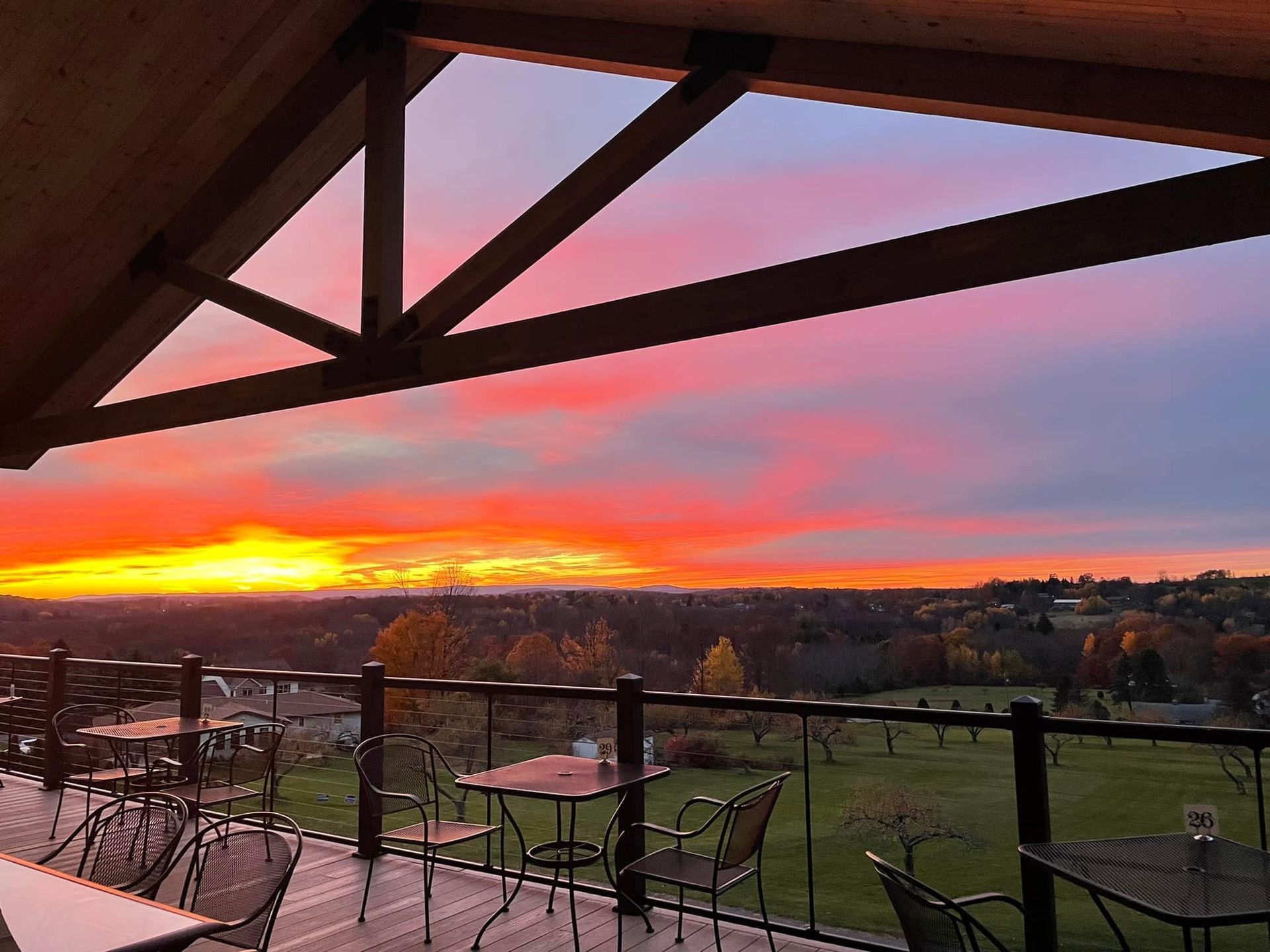 A balcony view from the winery with tables and chairs overlooking a sunset.