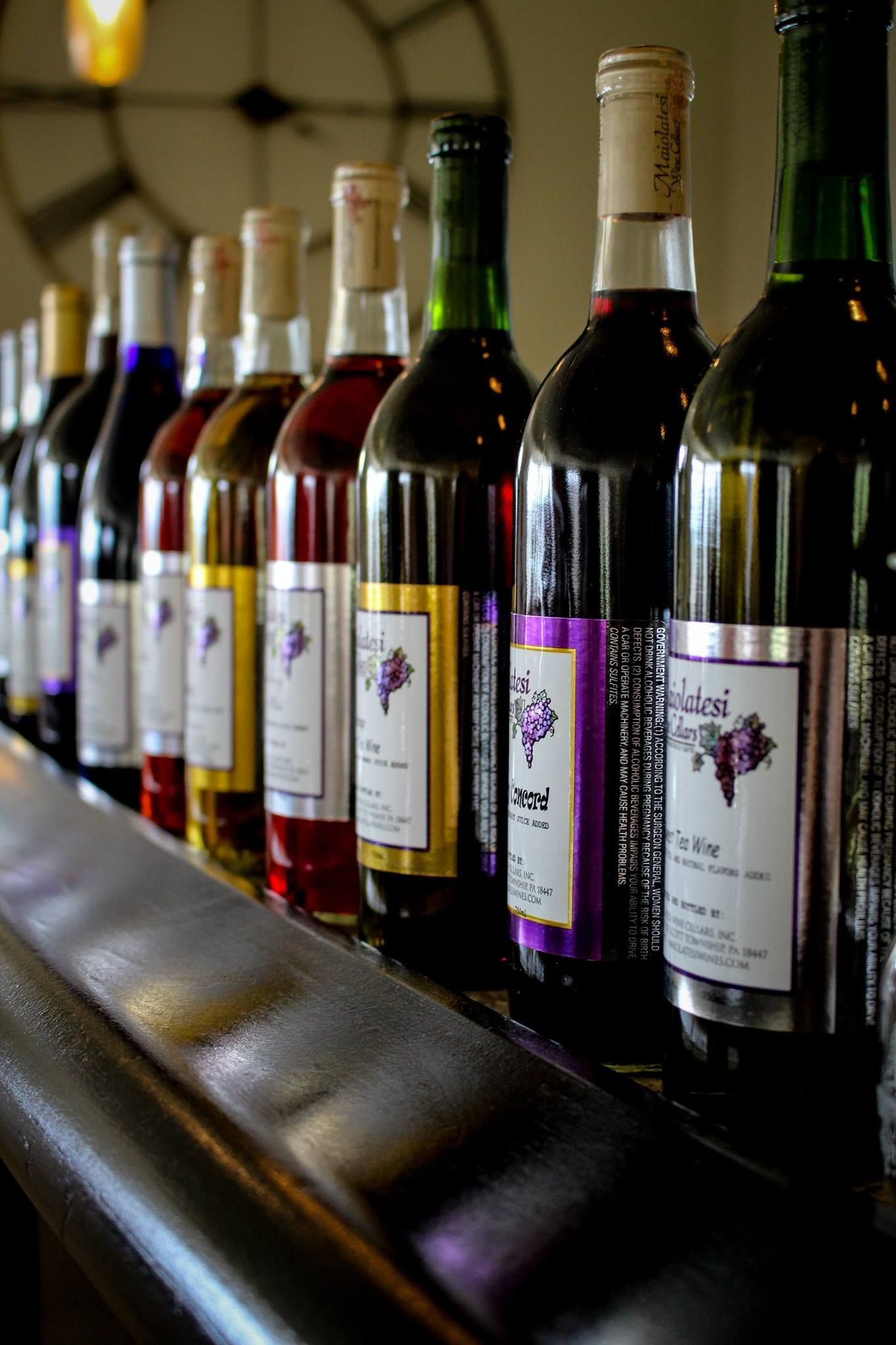 A row of wine bottles are lined up on a bar.