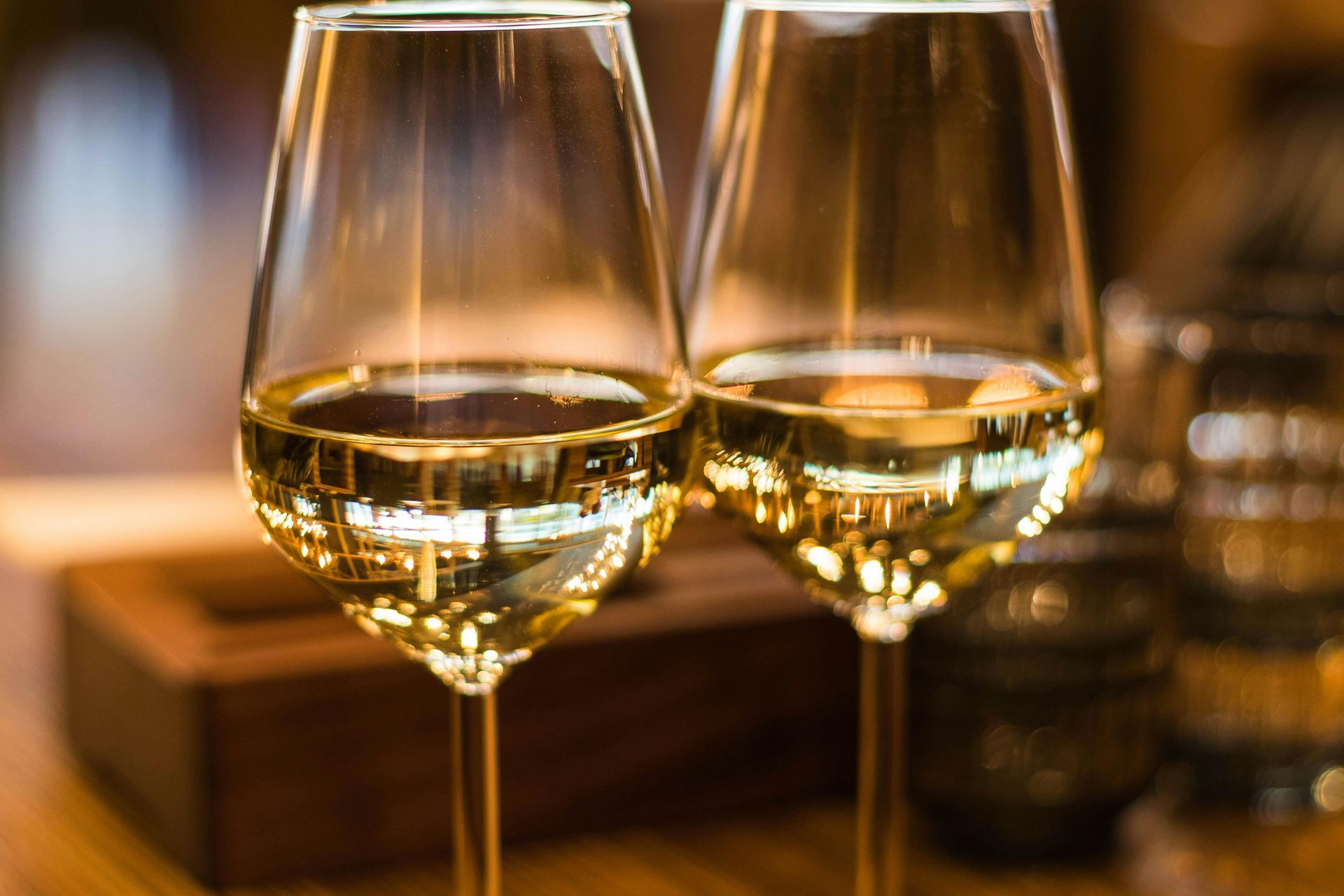 Two glasses of white wine are sitting on a wooden table.