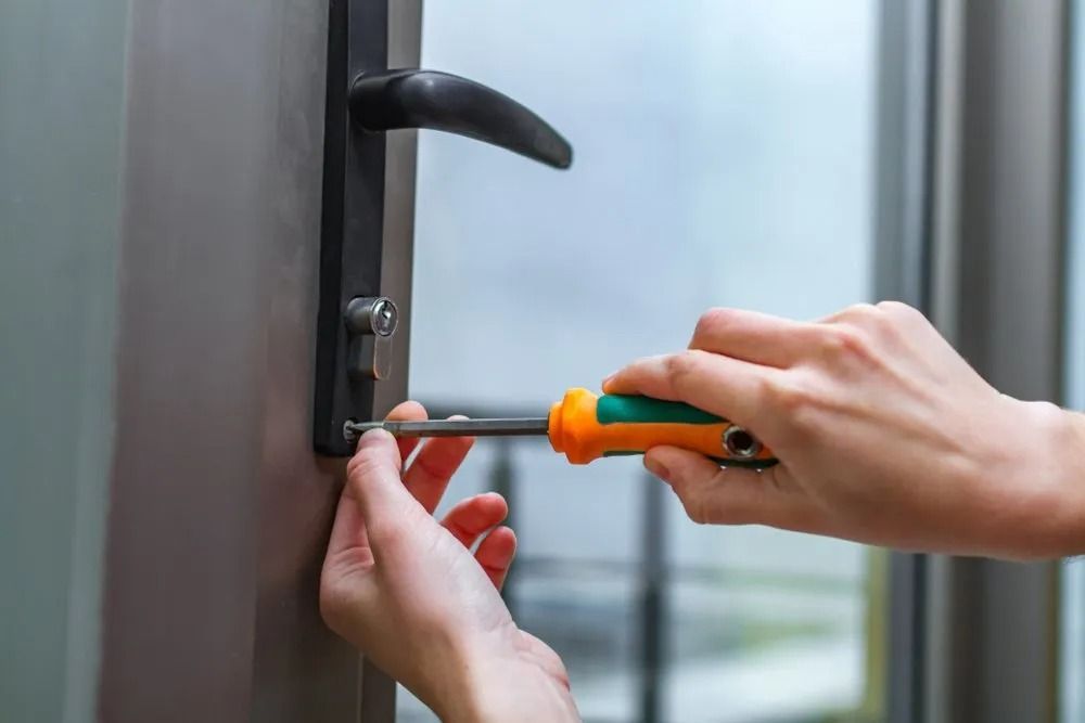 Person Using a Screwdriver to Tighten a Screw on a Door Handle — CTS Locksmiths in Aura, QLD