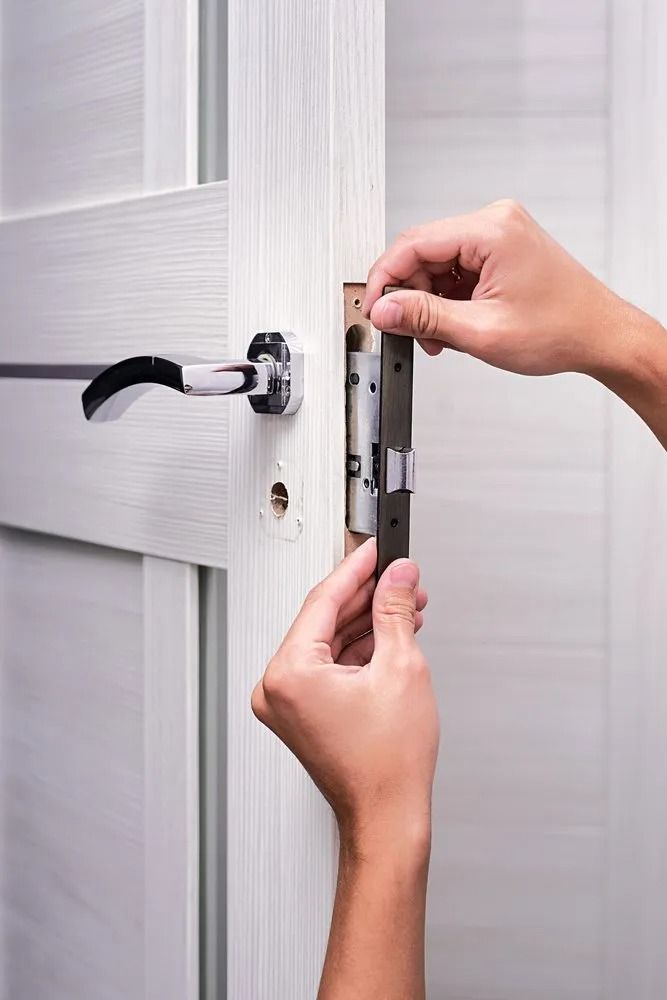 Hands Installing a Door Latch on a White Door — CTS Locksmiths in Maroochydore, QLD