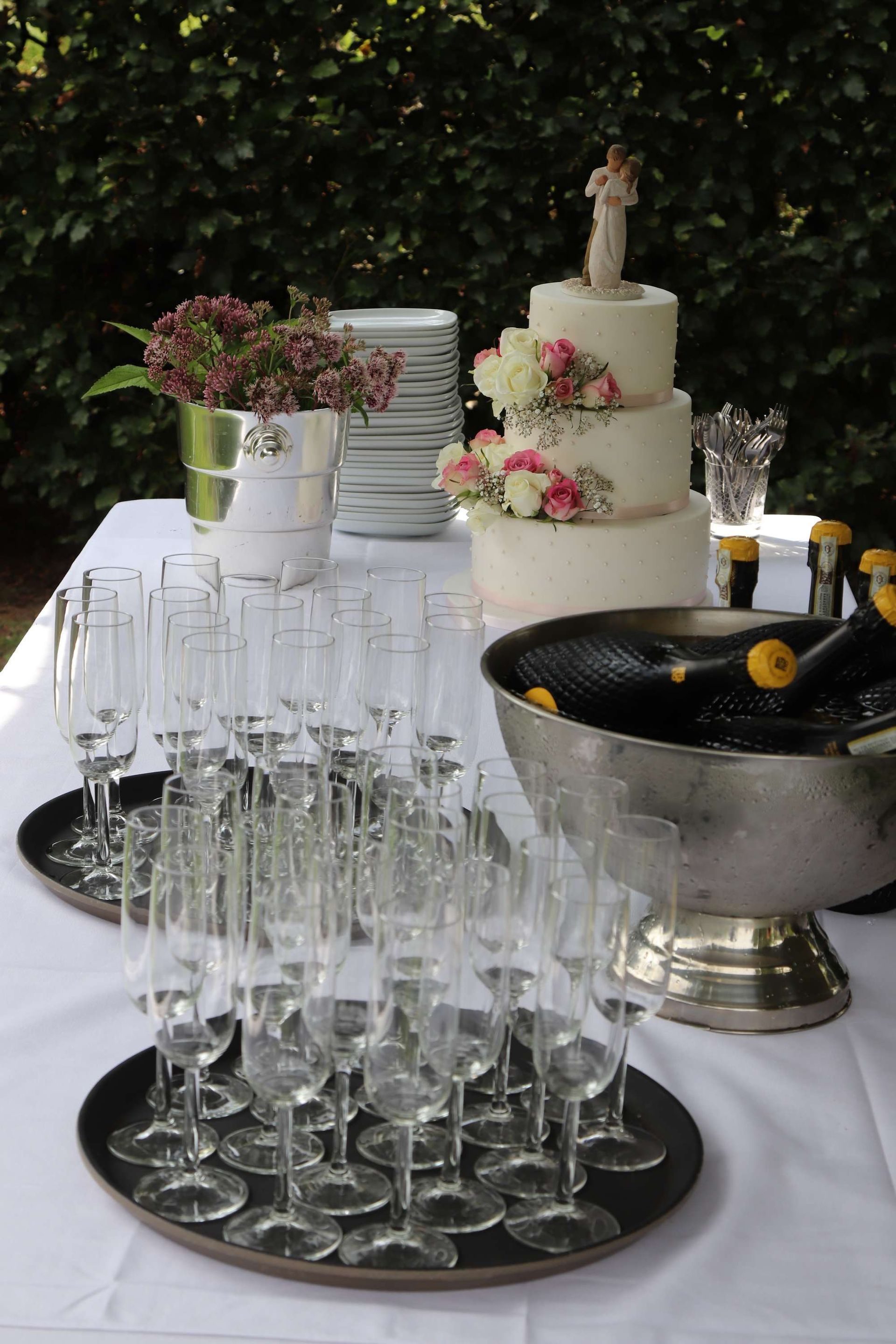 Bruiloftstafel met bruidstaart, champagneglazen en bloemversieringen.