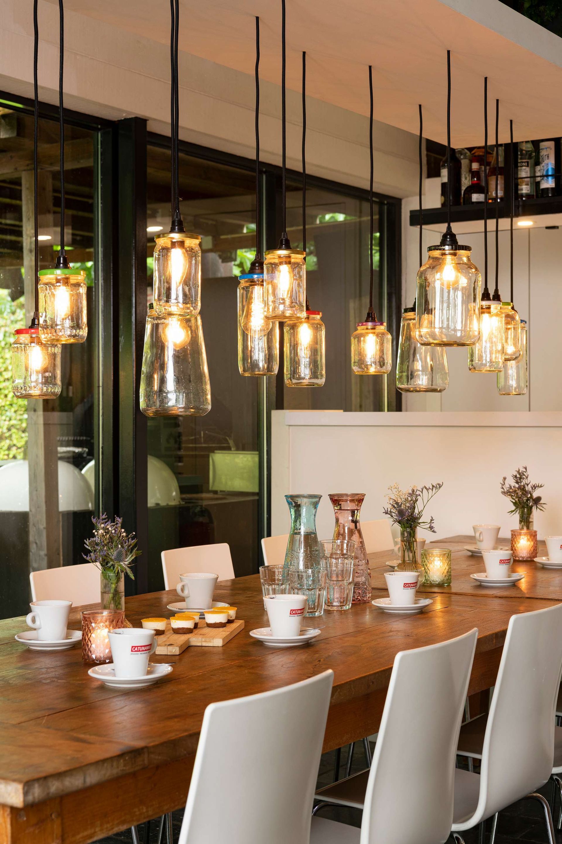 Een eetkamer met een lange houten tafel en witte stoelen